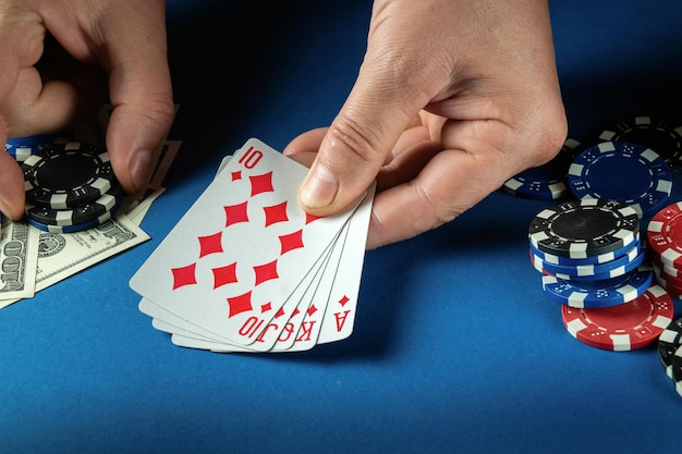 Le joueur parie sur une combinaison gagnante quinte flush royale dans un jeu de poker sur une table bleue avec des jetons