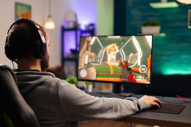 Joueur professionnel avec casque jouant à un jeu vidéo avec des graphismes modernes pour la compétition de tir. Cyber streaming en ligne lors d'un tournoi de jeu à l'aide d'un réseau technologique sans fil