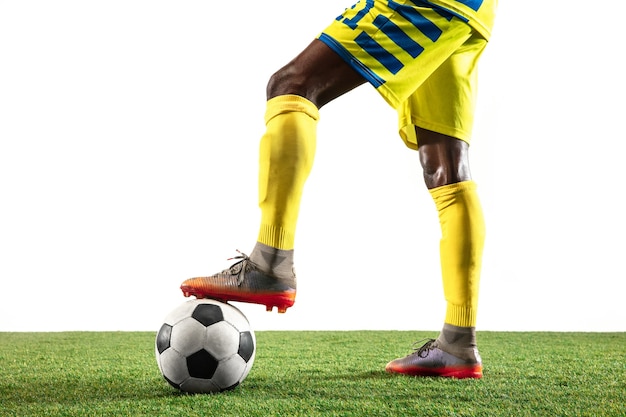 Joueur professionnel de football ou de football afro-américain de l'équipe jaune en mouvement isolé sur fond de studio blanc. Fit l'homme en action, excitation, moment émotionnel. Concept de mouvement au gameplay.