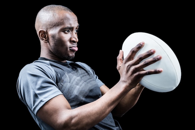 Joueur de rugby à la recherche loin tout en jetant la balle sur fond noir