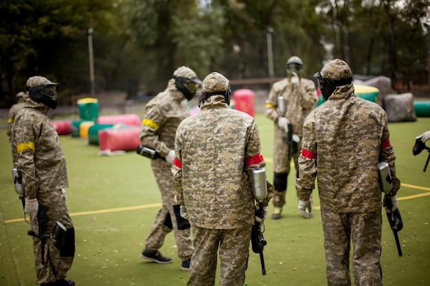 Joueur de sport de paintball en uniforme de protection et masque jouant avec une arme à feu à l'extérieur