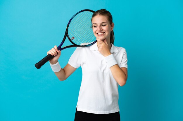 Joueur de tennis jeune femme sur bleu regardant sur le côté et souriant