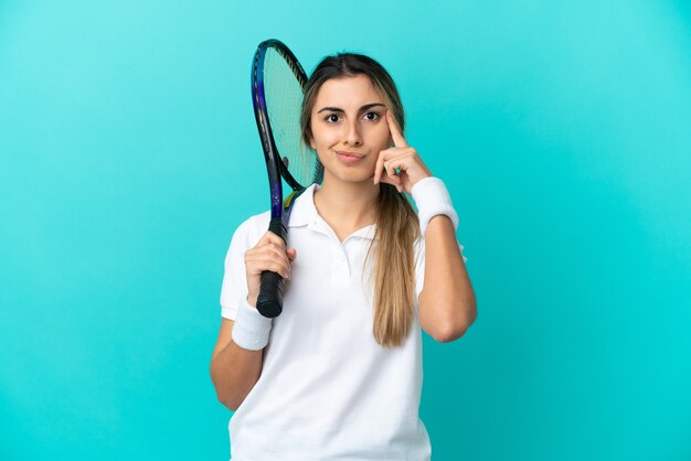 Joueur de tennis jeune femme isolée sur fond bleu pensant une idée