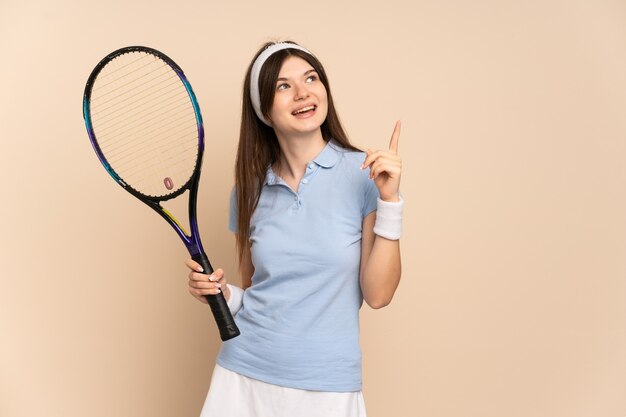 Joueur de tennis jeune fille sur mur isolé pointant vers le haut une excellente idée