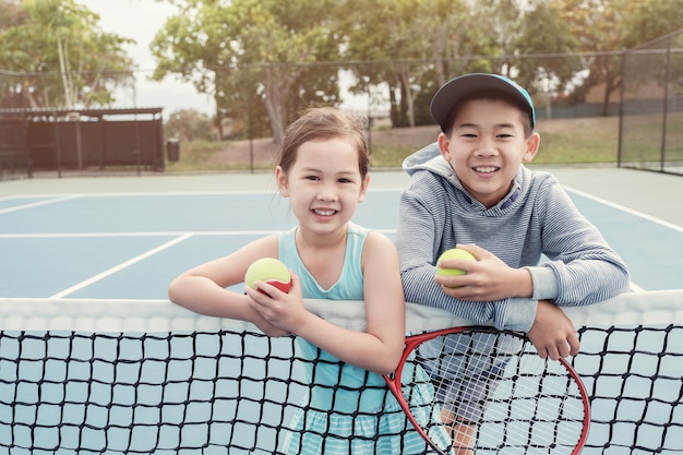 Joueur de tennis de jeunes enfants asiatiques sur le court bleu