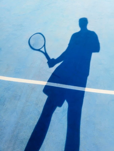 Joueur de tennis et ombre sur un court de tennis, fond de tennis