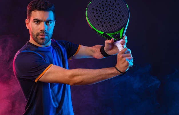 Joueur de tennis à padel avec raquette homme athlète avec raquette à padel sur le terrain avec des couleurs au néon sport