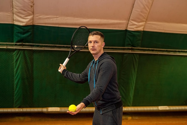 Un joueur de tennis professionnel frappe le tennis sur un court de tennis intérieur tôt le matin