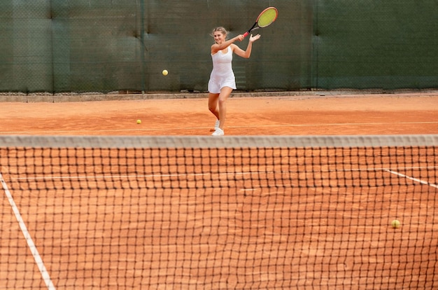 Joueur de tennis en tenue de sport blanche se préparant à servir la formation de balle de tennis avant le match