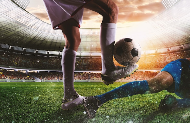 Joueurs de football avec soccerball au stade illuminé pendant le match