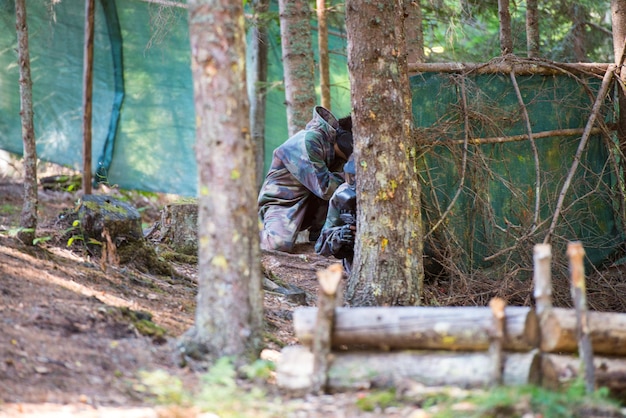 Les joueurs de paintball se cachent derrière l'arbre