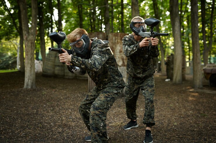 Photo joueurs de paintball en uniforme et masques jouant sur une aire de jeux dans la forêt. sport extrême avec arme pneumatique et balles ou marqueurs de peinture, jeu d'équipe militaire à l'extérieur, tactiques de combat