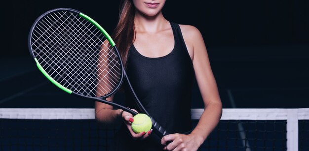 Joueuse avec raquette de tennis et balle assise près du filet