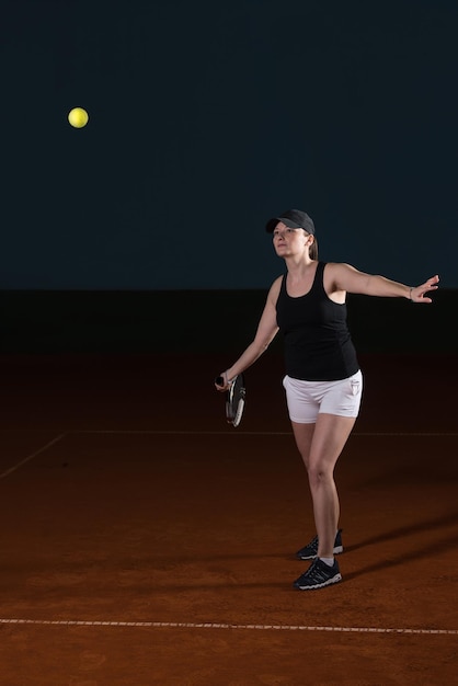 Joueuse de tennis atteignant pour frapper la balle de tennis sur le court