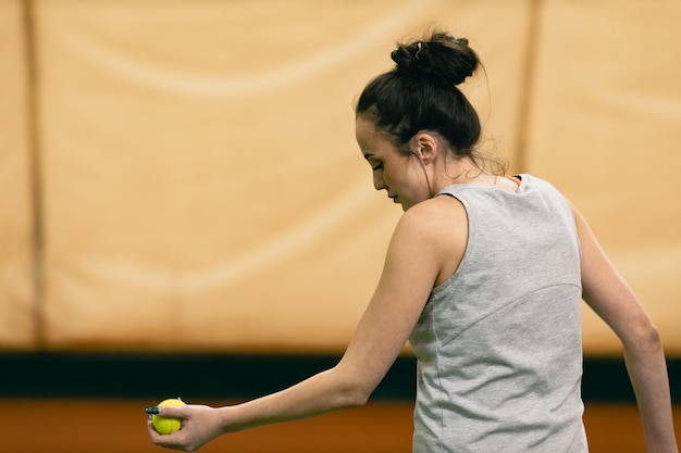 Joueuse de tennis jouant à l'entraînement avec raquette et balle au tribunal