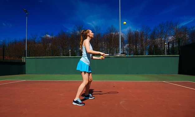 joueuse de tennis en robe blanche et talons tenant une raquette de tennis sur le court. Jeune femme joue au tennis, sport