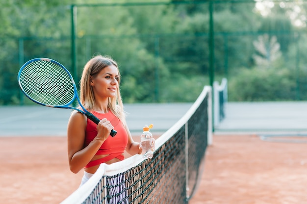 Joueuse de tennis avec une serviette sur ses épaules l'eau potable après le match