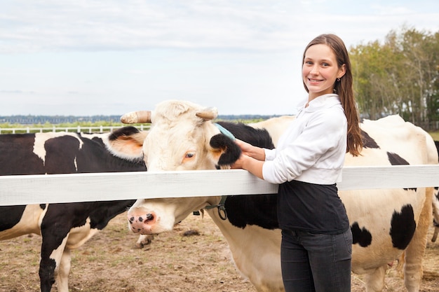 Jouez avec les animaux, amitié avec la vache. Agriculteur souriant debout près du bétail à l'extérieur. Extérieur, automne