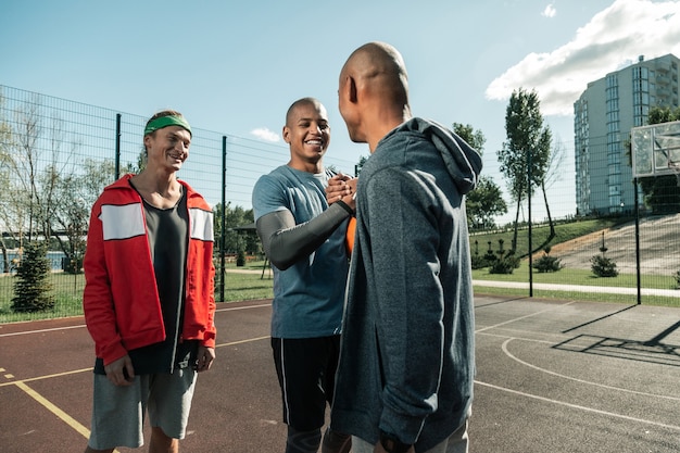 Photo jouons. des gens joyeux et positifs se rencontrent sur le terrain de basket en y venant pour jouer