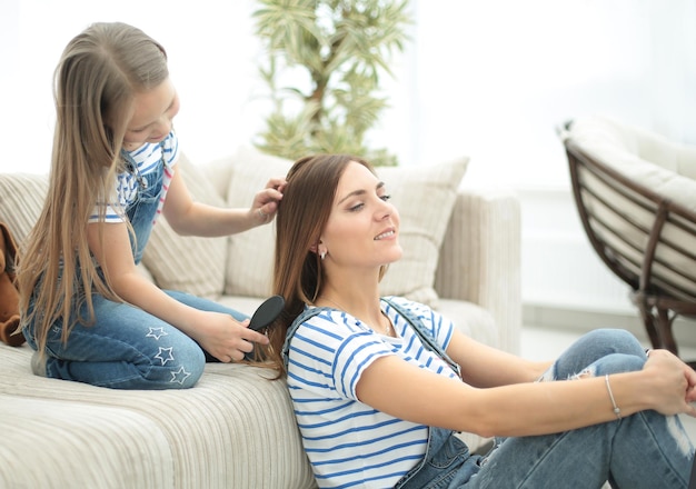 Jour de la beauté Une petite fille coiffe les cheveux de sa mère