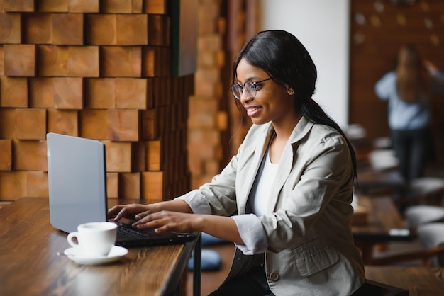 Jour de chance. Femme noire émotionnelle regardant un ordinateur portable, serrant les poings et criant, travaillant au café, espace de copie