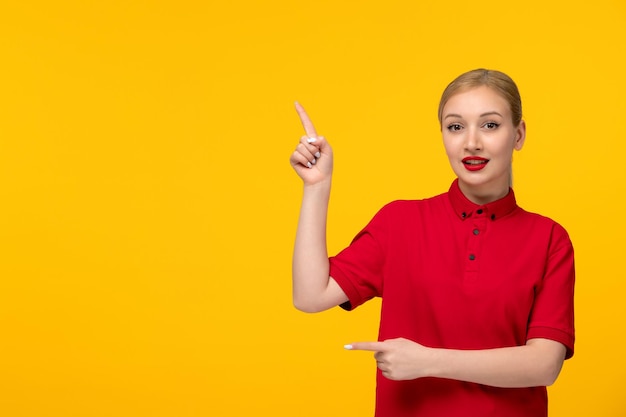 Jour de chemise rouge jolie fille tenant son doigt vers le haut dans une chemise rouge sur fond jaune