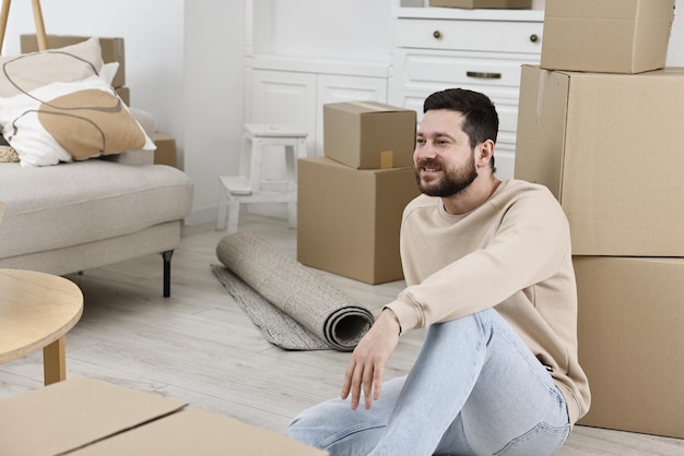 Jour de déménagement Un homme se repose sur le sol près de boîtes de carton dans sa nouvelle maison