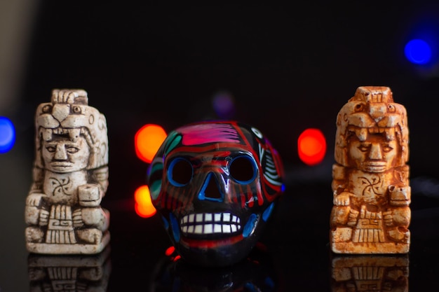 Jour du crâne mexicain des morts et deux sculptures aztèques sur fond noir