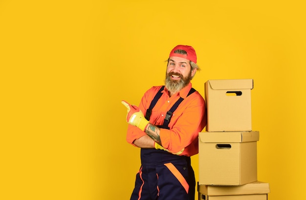 Jour du déménagement Déballage des cartons de déménagement Homme barbu coursier tenir les cartons Déménagement dans un nouvel appartement Service postal Chargeur barbu en uniforme Préparation de la rénovation Hipster barbu à l'intérieur Immobilier