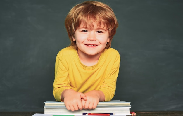 Le jour du professeur. Mignon petit garçon d'âge préscolaire dans une salle de classe. Heureux élèves souriants dessinant au bureau. Un écolier ou un enfant d'âge préscolaire apprend.