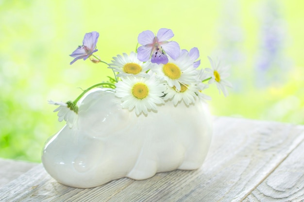 Un jour ensoleillé sur un fond en bois clair est un vase sous forme d'hippopotame avec des fleurs sauvages