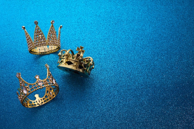 Photo jour de l'épiphanie ou dia de reyes magos concept trois couronnes en or sur un fond bleu étincelant