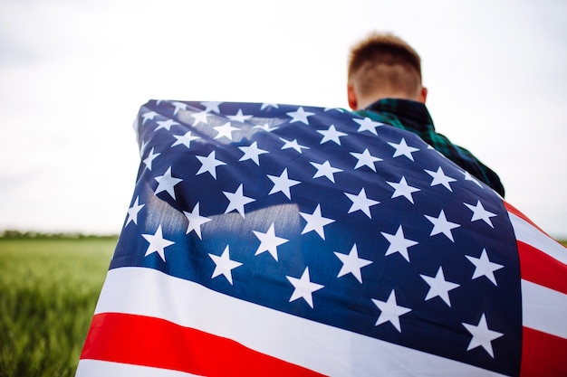 Jour de l'indépendance. Un homme en chemise à carreaux avec un drapeau américain dans un champ.