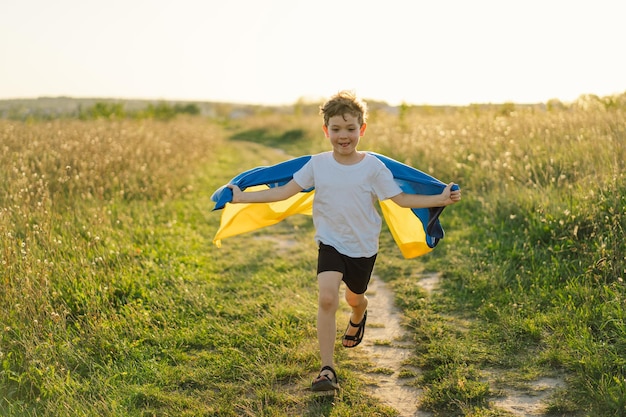 Jour de l'indépendance de l'Ukraine Enfant garçon ukrainien en t-shirt blanc avec le drapeau jaune et bleu de l'Ukraine dans le champ Drapeau de l'Ukraine Jour de la Constitution Debout avec l'Ukraine Sauvez l'Ukraine