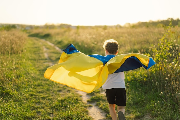 Jour de l'indépendance de l'Ukraine Enfant garçon ukrainien en t-shirt blanc avec le drapeau jaune et bleu de l'Ukraine dans le champ Drapeau de l'Ukraine Jour de la Constitution Debout avec l'Ukraine Sauvez l'Ukraine