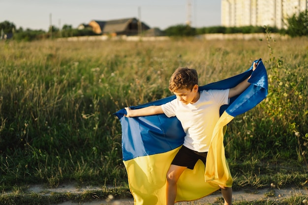 Jour de l'indépendance de l'Ukraine Enfant garçon ukrainien en t-shirt blanc avec le drapeau jaune et bleu de l'Ukraine dans le champ Drapeau de l'Ukraine Jour de la Constitution Debout avec l'Ukraine Sauvez l'Ukraine