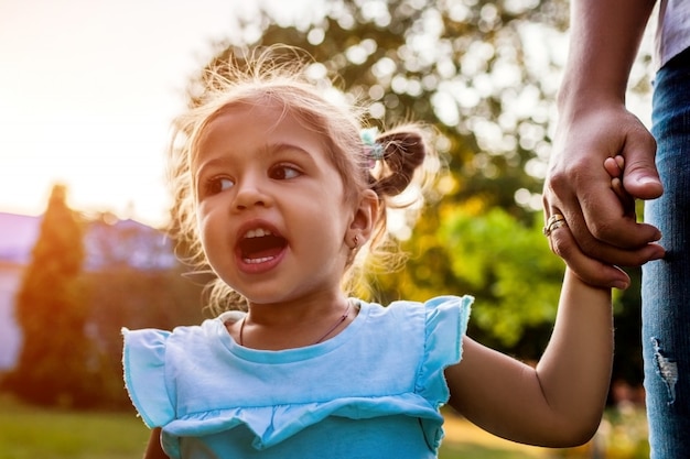 Le jour de Motehr. Petite fille enfant en bas âge criant à l'extérieur. Mère tenant la main de sa fille dans le parc.