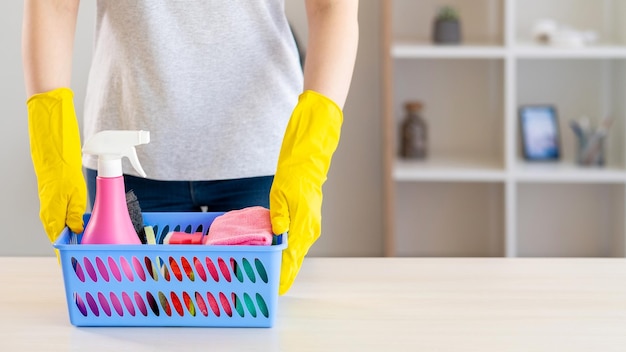 Jour de nettoyage Routine de la femme au foyer Tâches ménagères Femme méconnaissable portant des gants de protection mettant un panier avec un nettoyant en aérosol des éponges savonneuses brossent un chiffon en microfibre sur l'espace de copie de la table