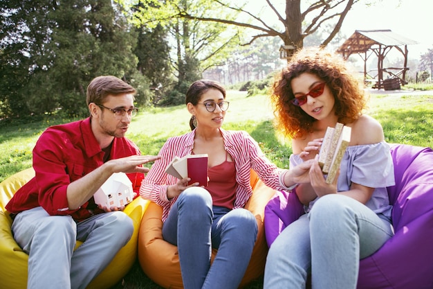 Jour ouvrable. Bel homme déterminé assis en plein air avec ses collègues et discutant de leur projet