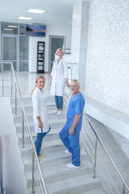 Jour ouvrable. Équipe de travailleurs médicaux souriants allant à l'étage