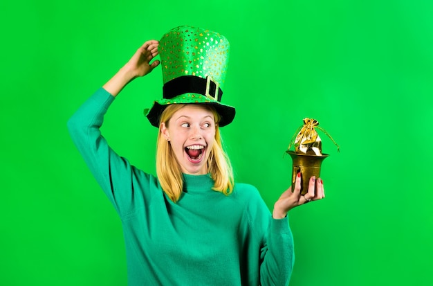 Le jour de la Saint-Patrick. Une fille souriante en costume de lutin tient un pot avec de l'or. Leprechaun tient un pot avec de l'or. Lutin vert. Le jour de la Saint-Patrick. Traditions irlandaises. La Saint-Patrick. Pot avec de l'or. Or.