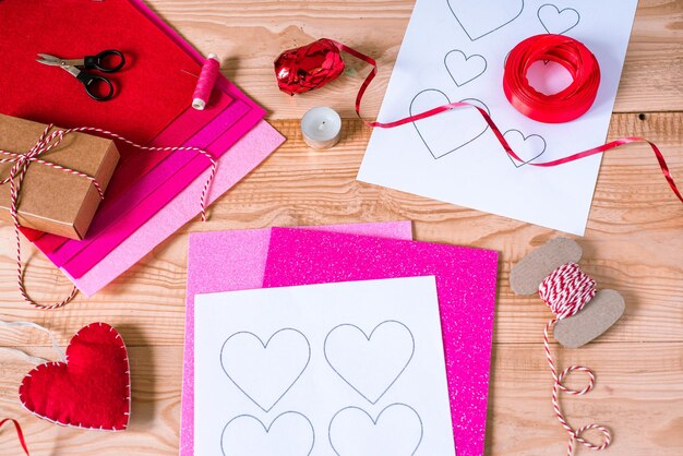 Photo jour de la saint-valentin fabriquant des cœurs et des décorations mady de feutre et de mousse sur fond de bois