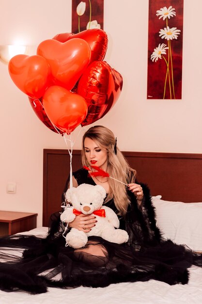 Jour de la Saint-Valentin Jour de la Femme Femme au lit dans un peignoir avec des ballons rouges