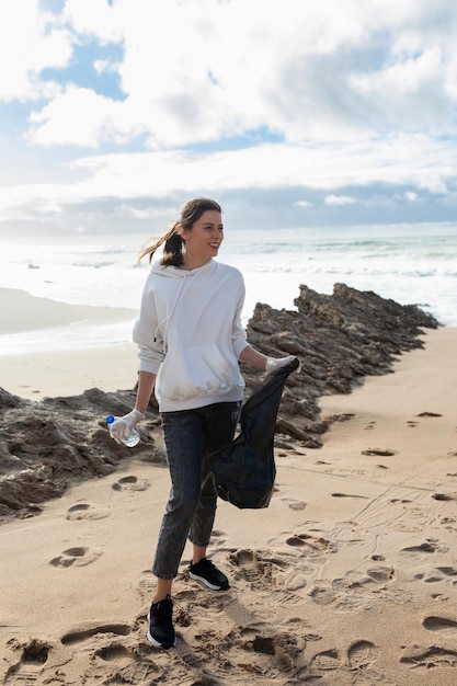 Jour de la terre Jeune militante mettant des bouteilles en plastique dans un sac poubelle nettoyant la zone côtière recadrée tir vertical