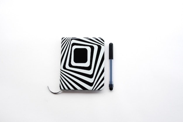 Un journal ou un cahier de conception cool en noir et blanc et un stylo sur fond blanc