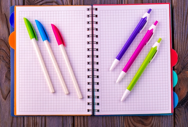 Journal (carnet) et stylos de couleur sur table en bois.