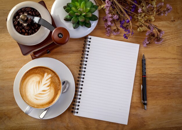 Journal, fleur et tasse de café sur une table en bois.