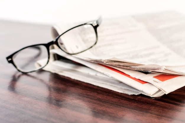 Journal et lunettes de lecture sur table en bois