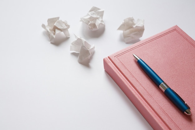 journal et stylo en métal sur des morceaux de papier froissés de table blanche. Erreurs dans la lettre