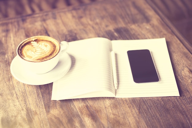 Journal vierge avec tasse de café et smartphone sur une table en bois effet photo vintage